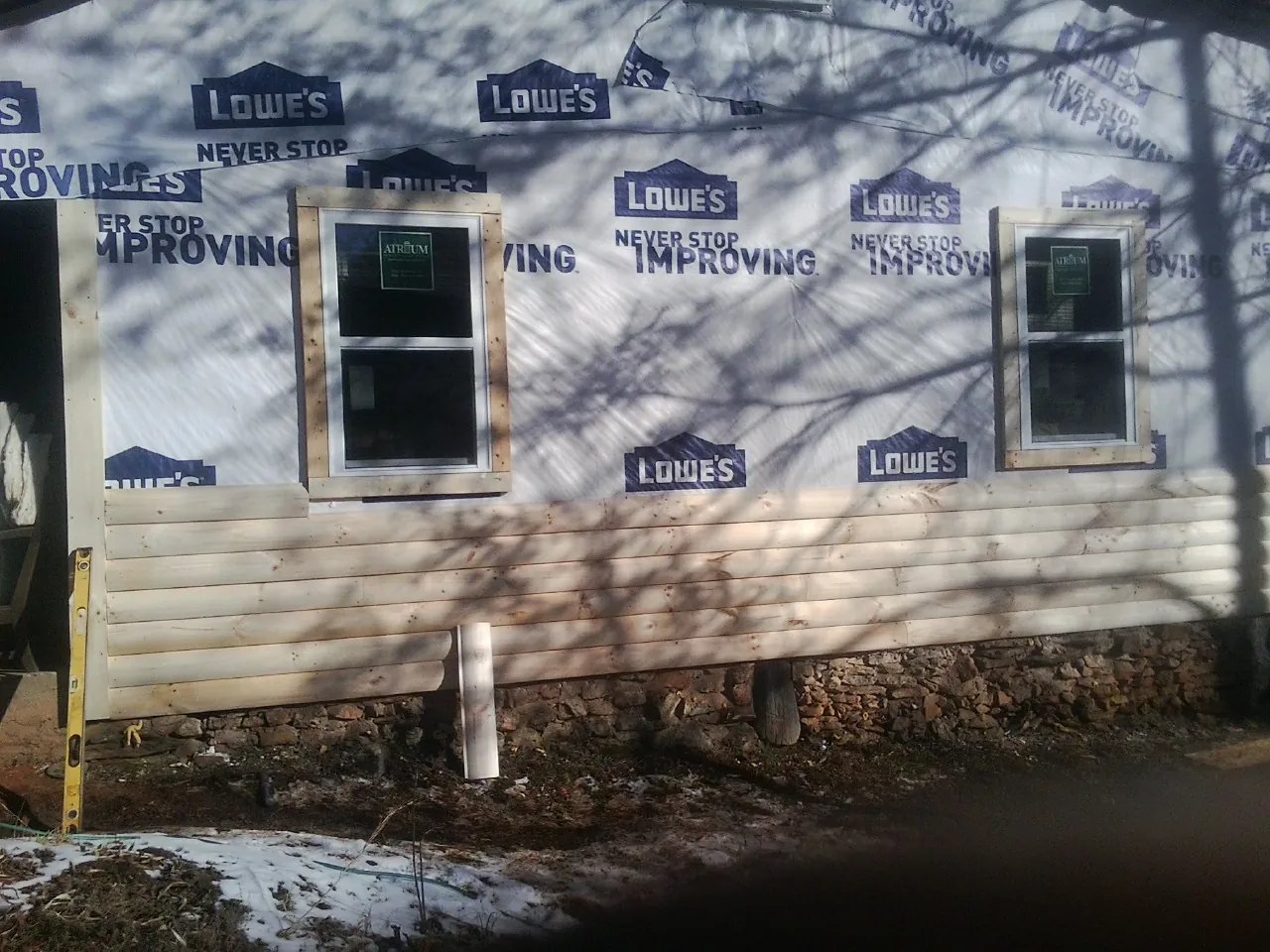 House wrap and new log siding going up on an exterior wall in West Finley