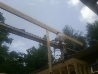 Carpenter setting a ridge beam over a new addition frame — Ice Dam Removal by Roofing Brothers in West Finley