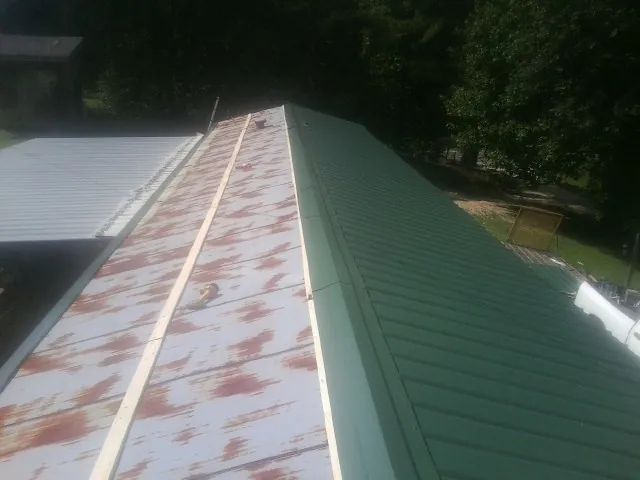 Old rusted panels beside newly installed green metal roofing — Wind Damage Roof Repair by Roofing Brothers in West Finley