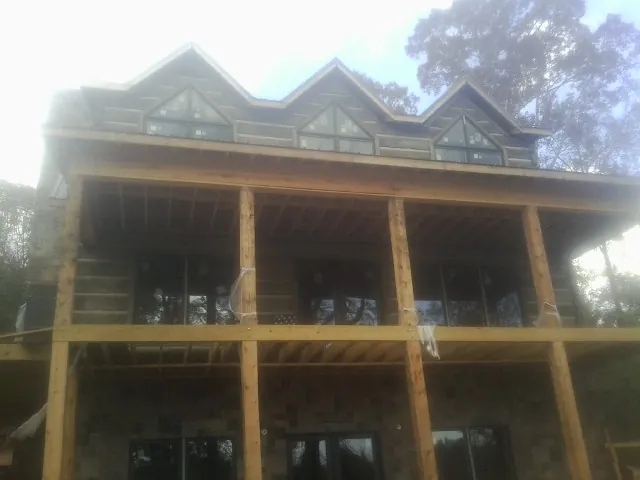 Dormers and porch framing on a large log home under construction — Roof Coating work by our crew in West Finley