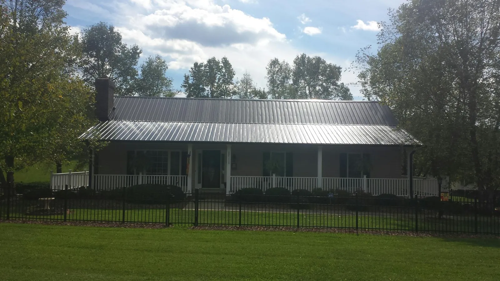 Gray metal roof on a brick ranch with a full width front porch — Gutter Guard Installation work by our crew in West Finley