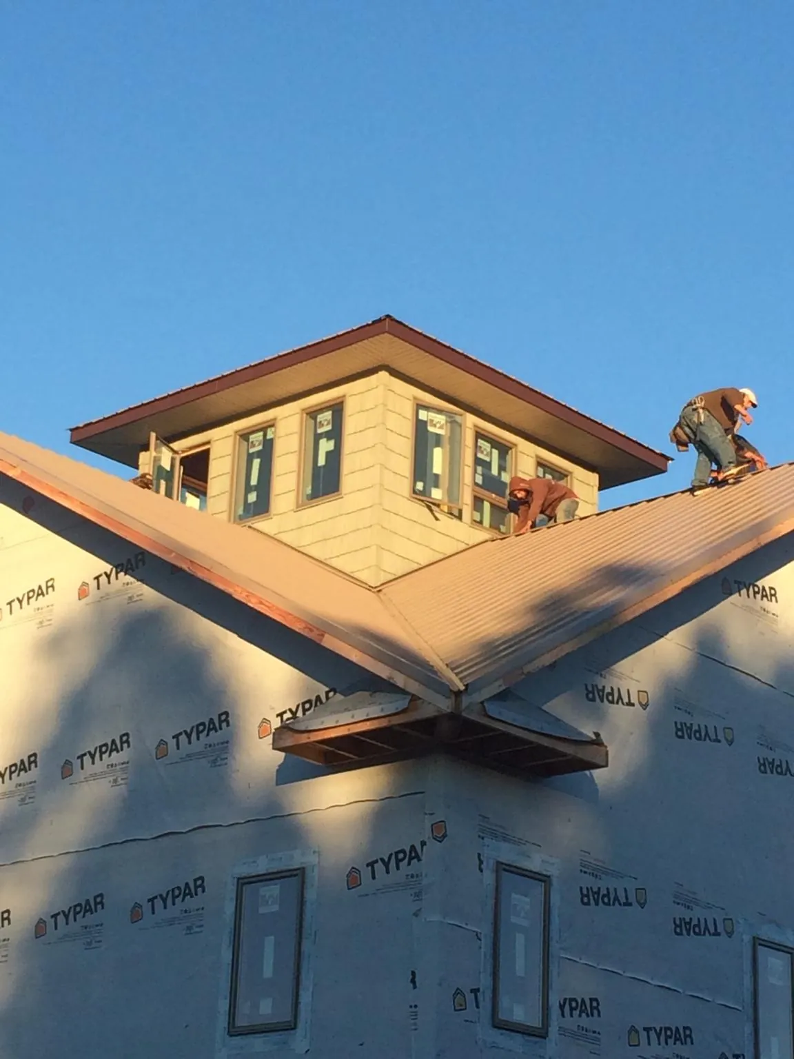 Roofers working around a rooftop cupola on a new metal roof at sunset — Roof Waterproofing in West Finley by Roofing Brothers